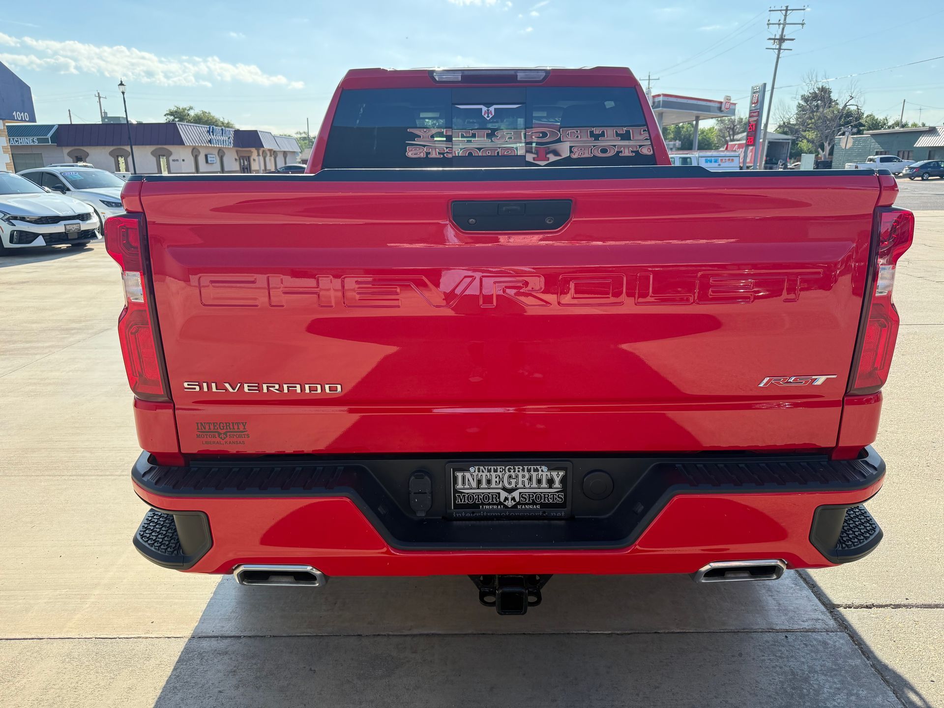 Red Chevrolet Silverado truck, rear view, parked outdoors on a sunny day.