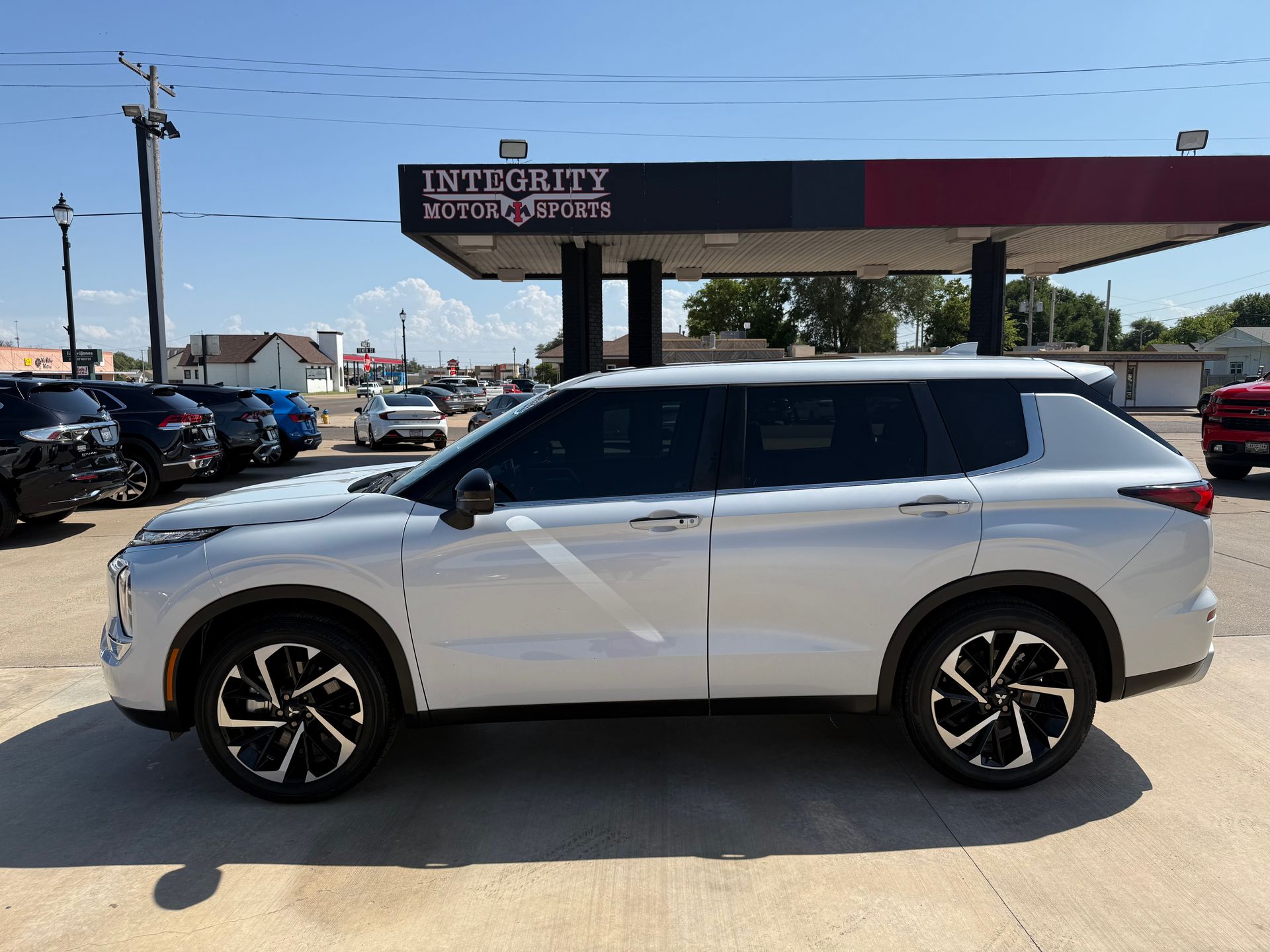 White SUV parked, dealership setting, sunny day.  