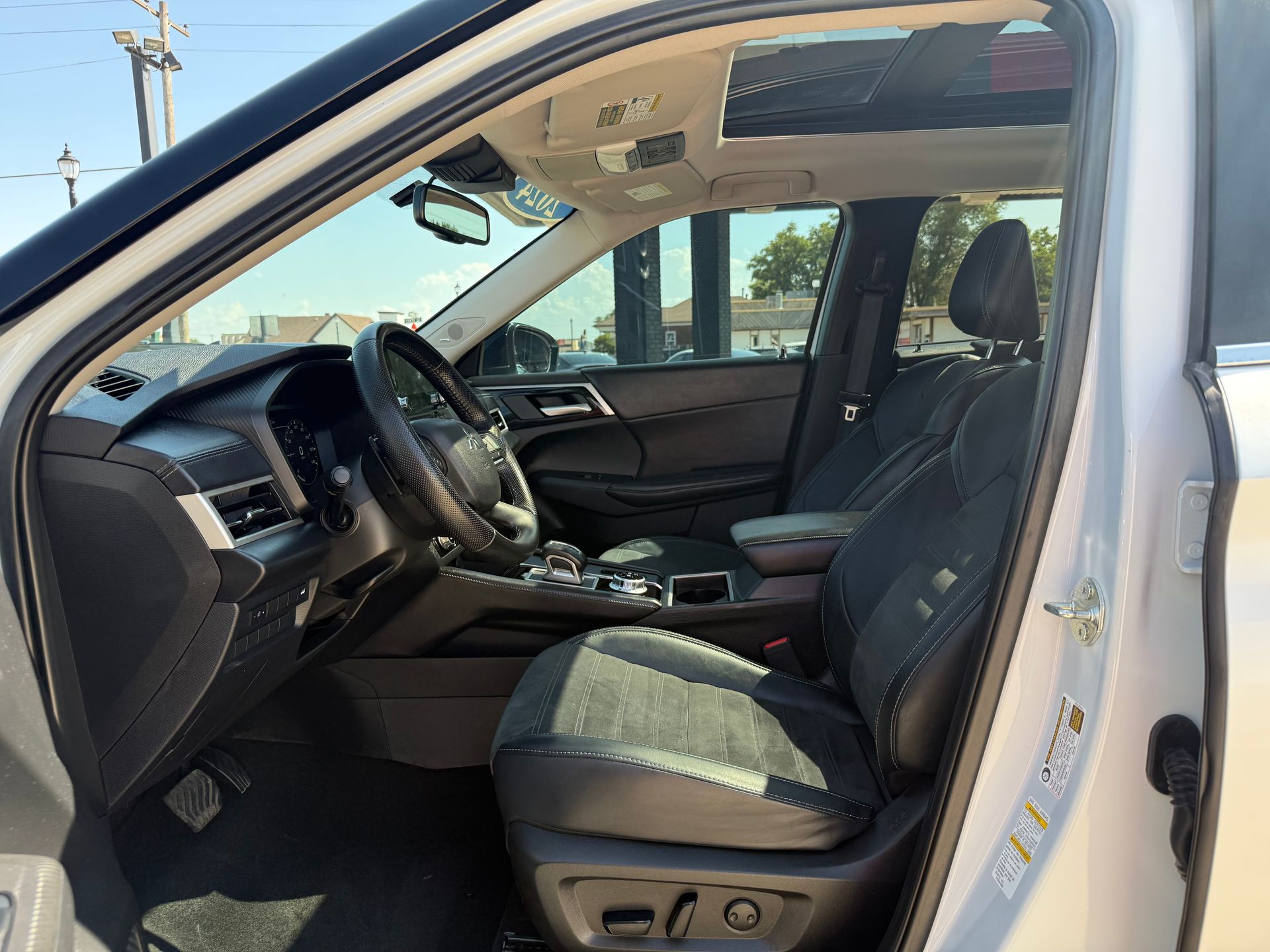 Interior view of a silver SUV with black seats, steering wheel, and dashboard. Driver's side door is open.