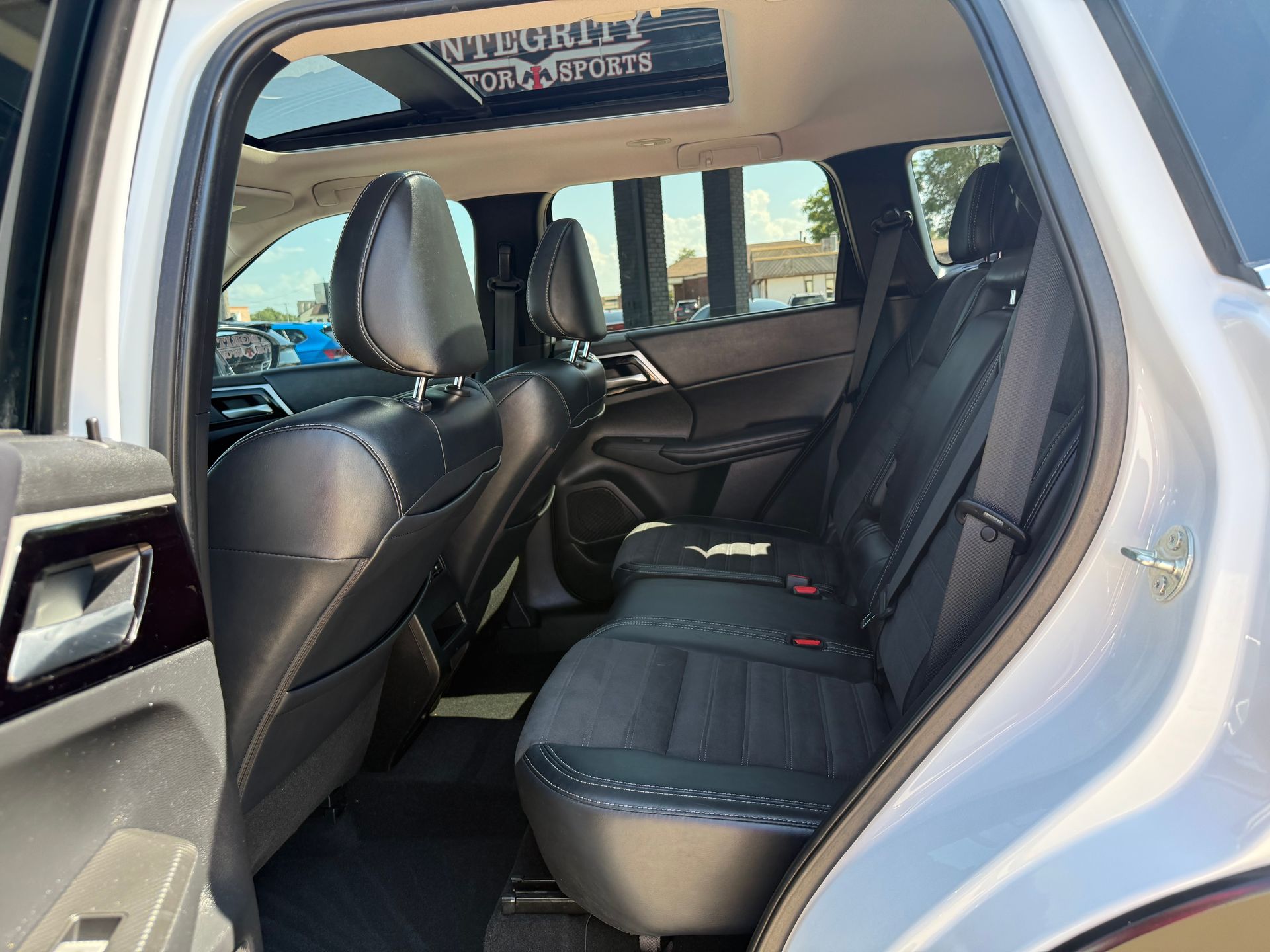 Interior rear view of a white SUV with black seats and a sunroof.