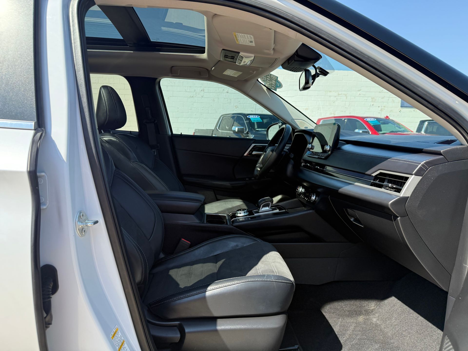 Interior view of a light gray SUV with black leather seats, dashboard, and sunroof.