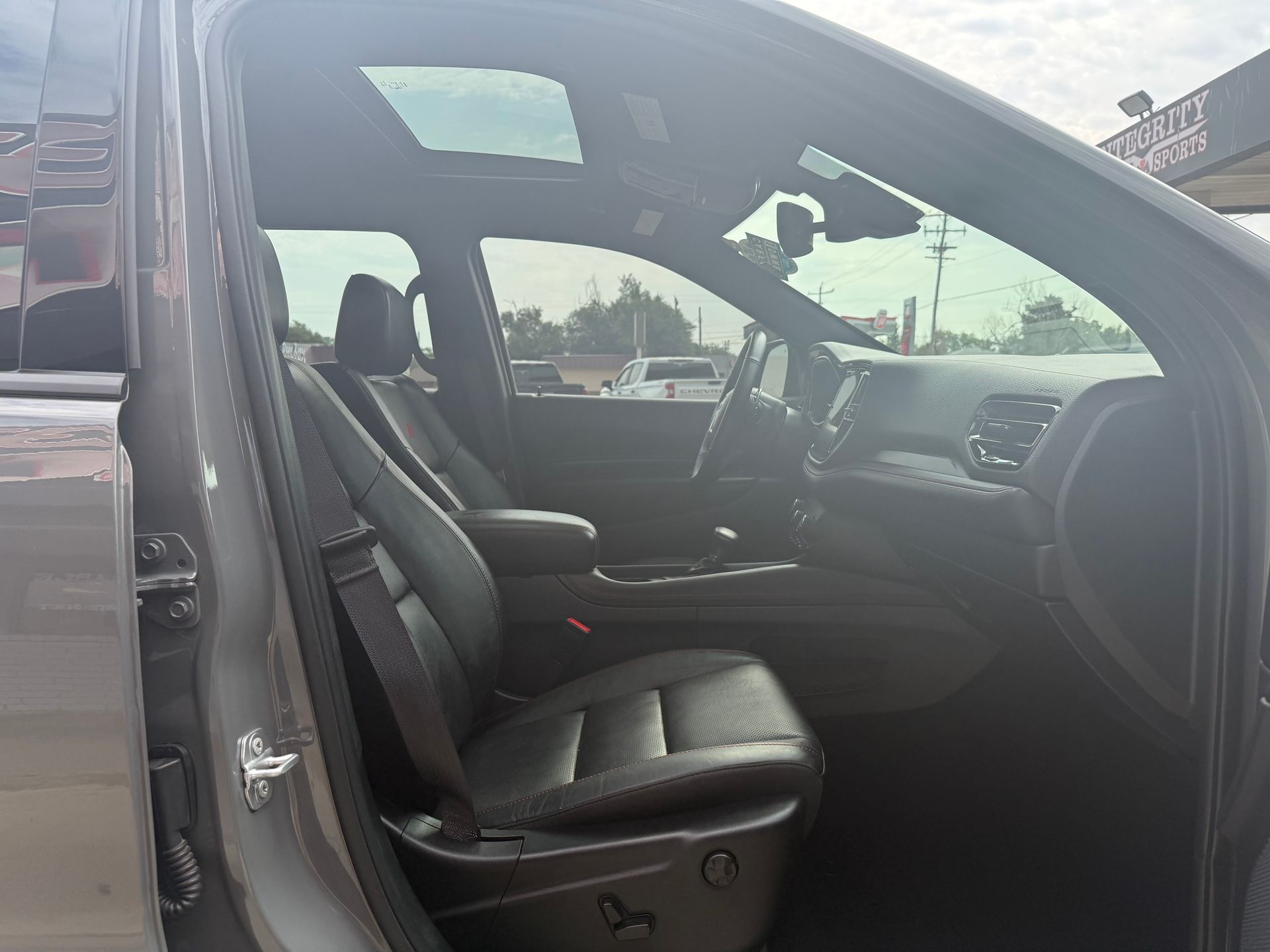 Gray car interior with black leather seats, sunroof, and steering wheel.