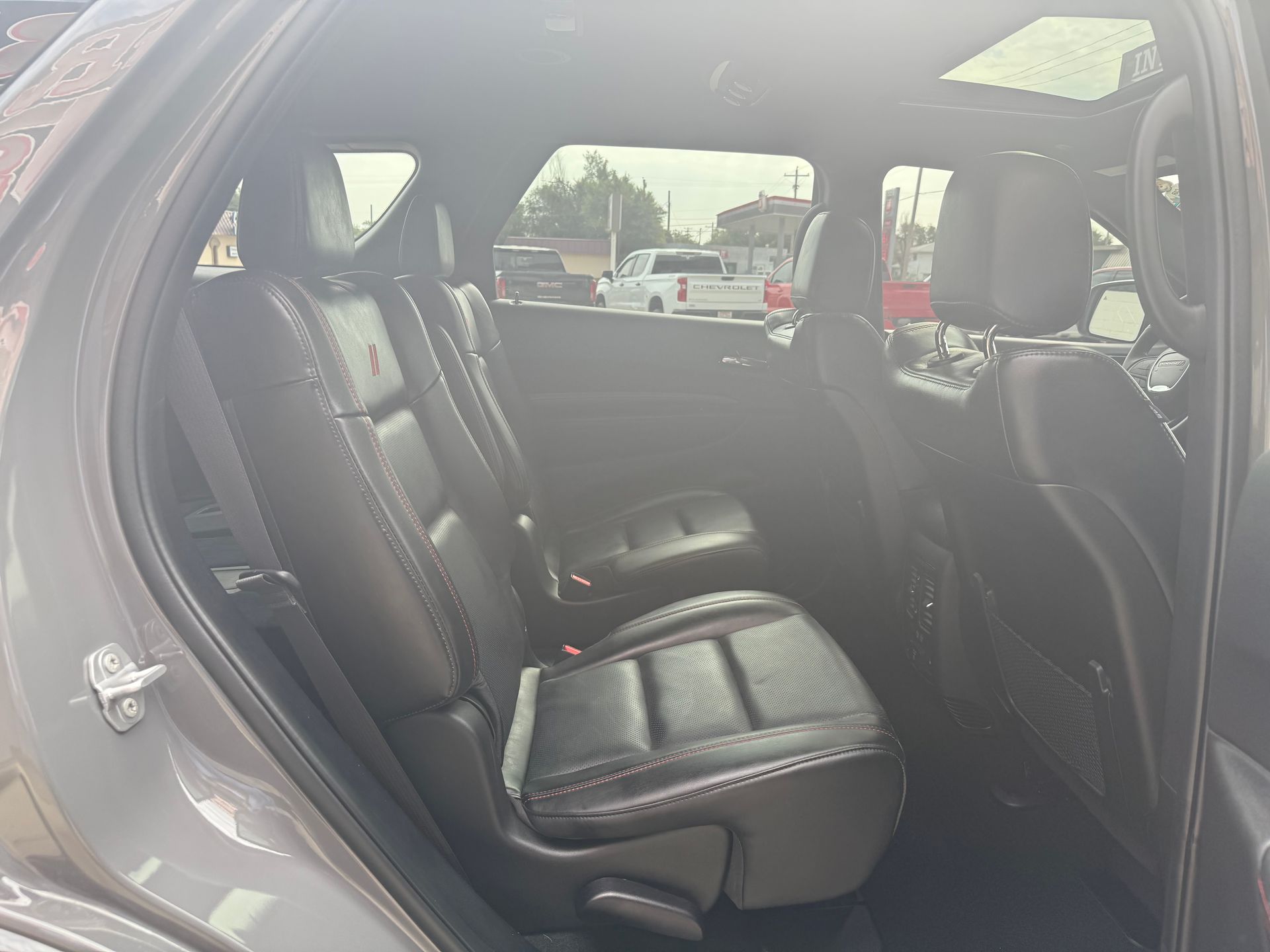 Inside view of a gray SUV with black leather seats, including the rear seats and sun roof.