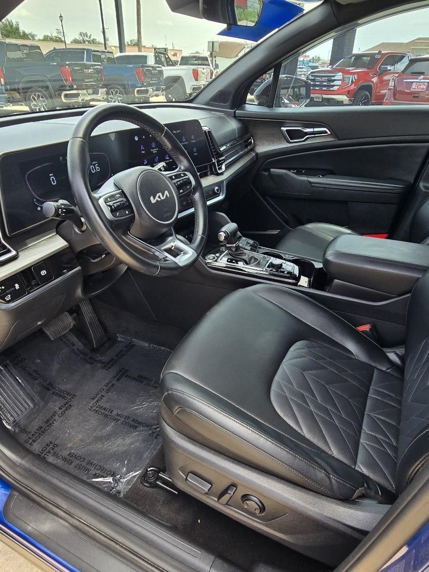 Car interior with black leather seats, steering wheel, and center console, viewed from the driver’s side.