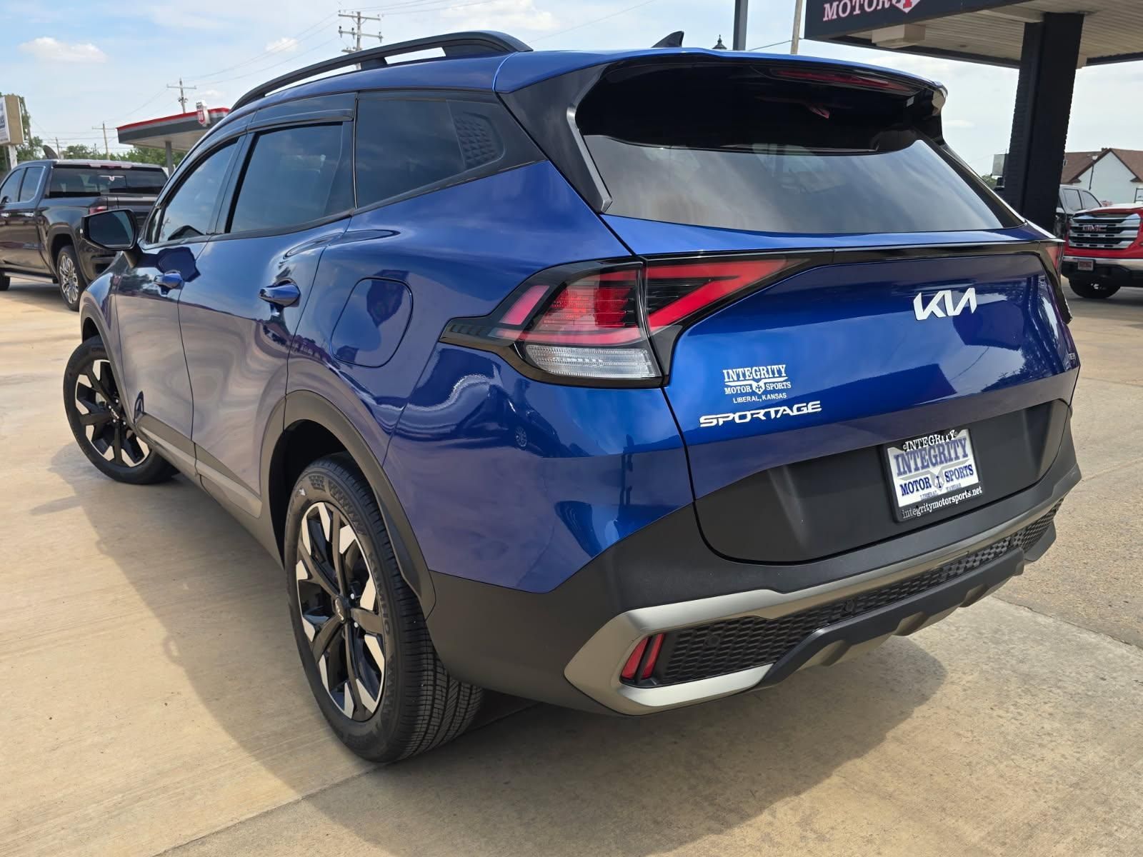Blue Kia Sportage SUV parked outdoors, rear three-quarter view under a canopy