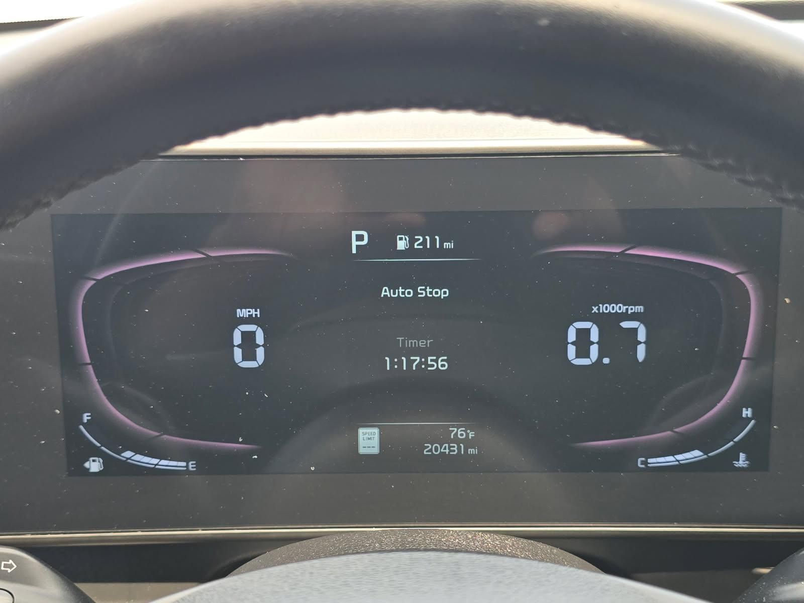 Car dashboard digital display showing speed 0, range 27 miles, and fuel/driver info on a dark screen
