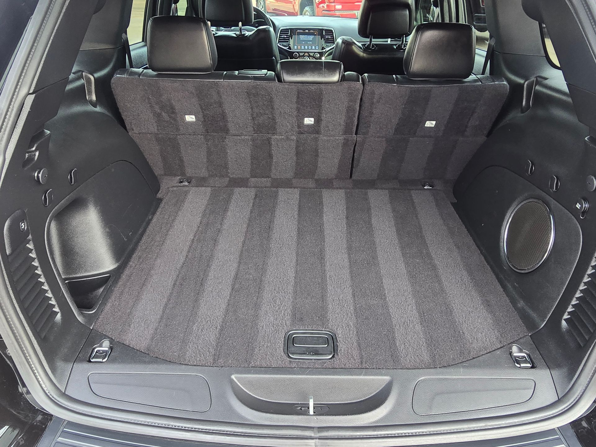 Clean, empty cargo area of a black SUV. Gray carpet with striped pattern.