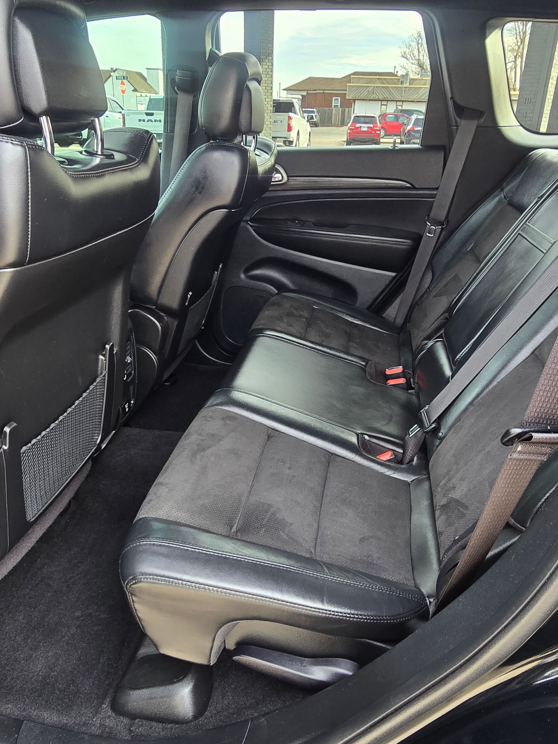 Black SUV back seats with leather and suede upholstery, dark carpet, and a mesh storage pocket.