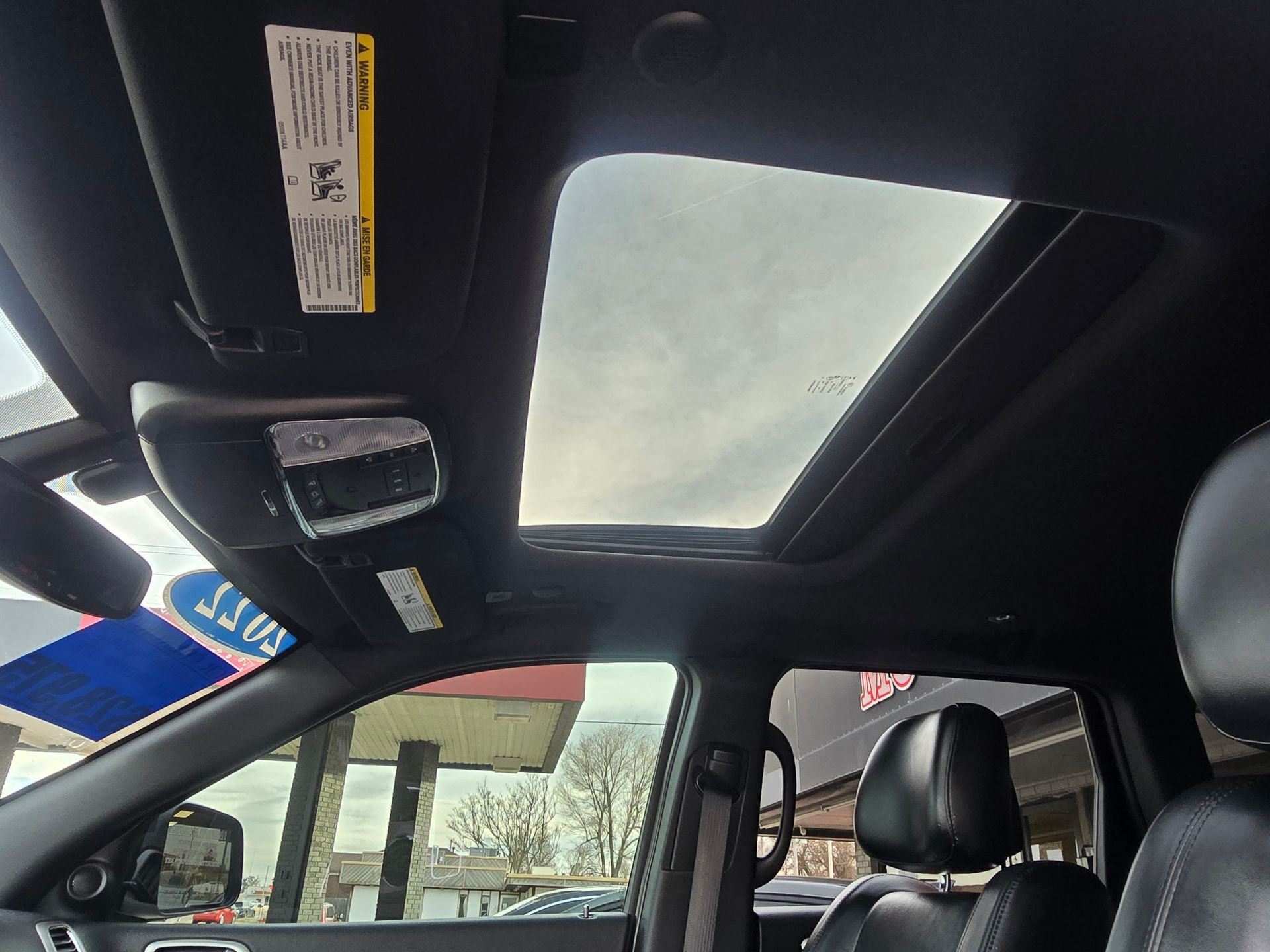 Interior car view with open sunroof, showing a cloudy sky.