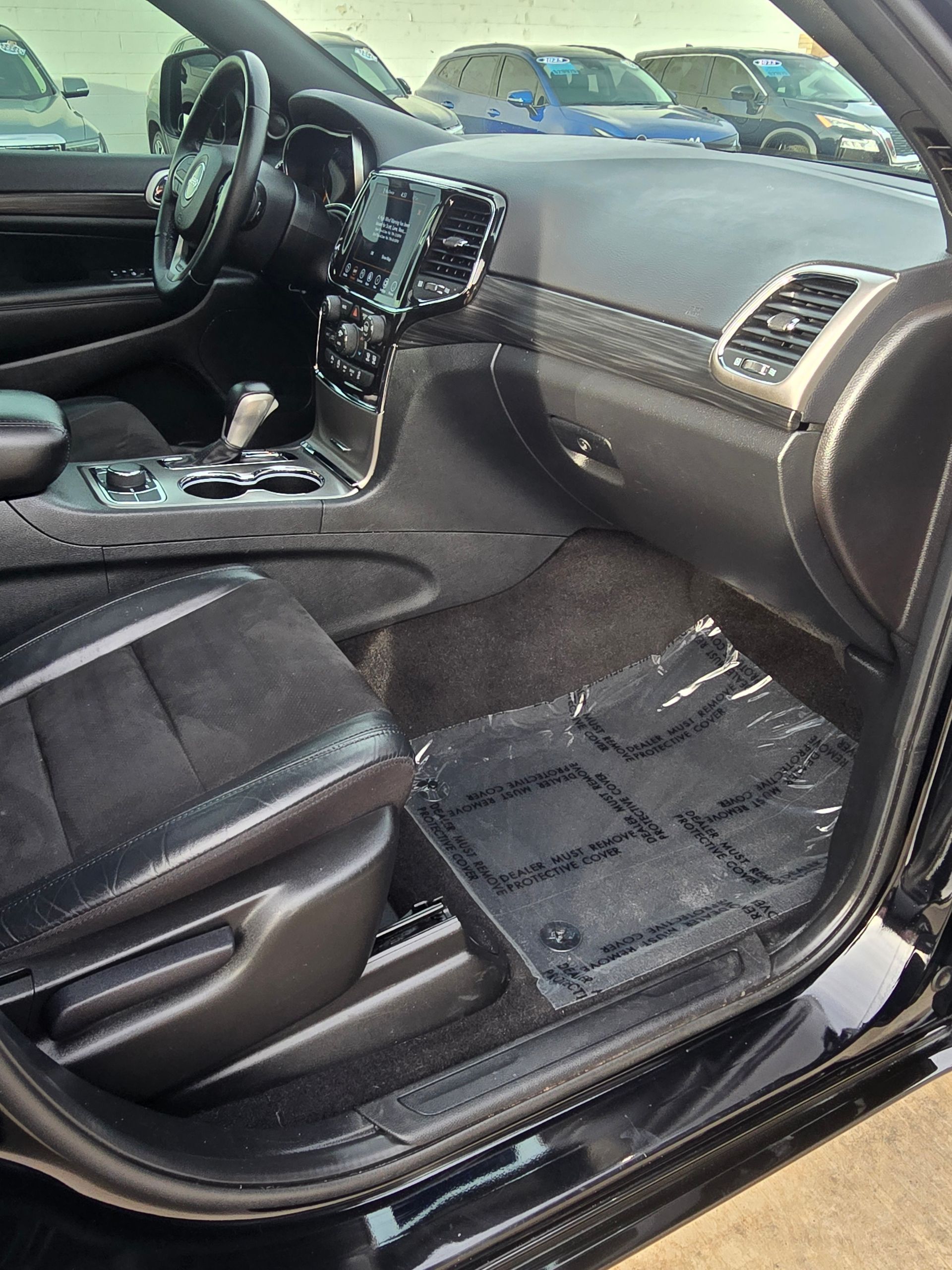 Black car interior with a dashboard, seats, and floor mat.