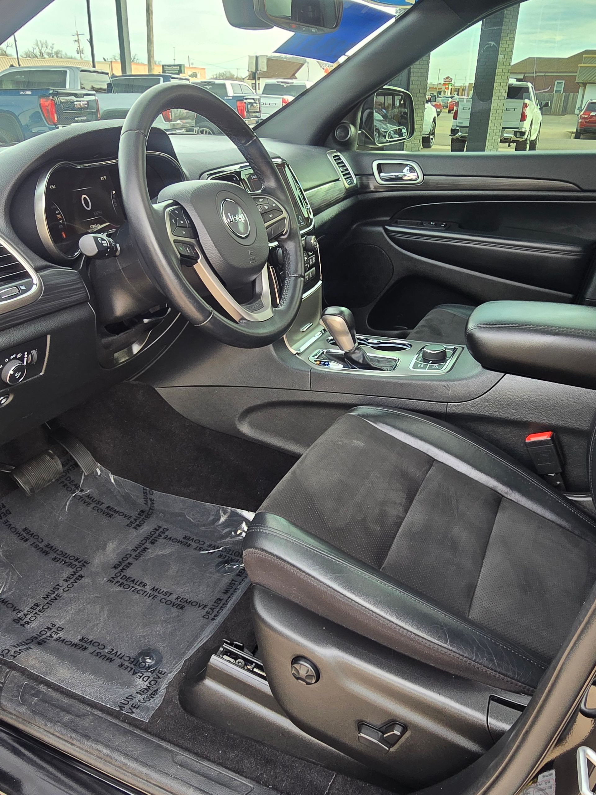 Black car interior with a leather and suede seat and steering wheel.