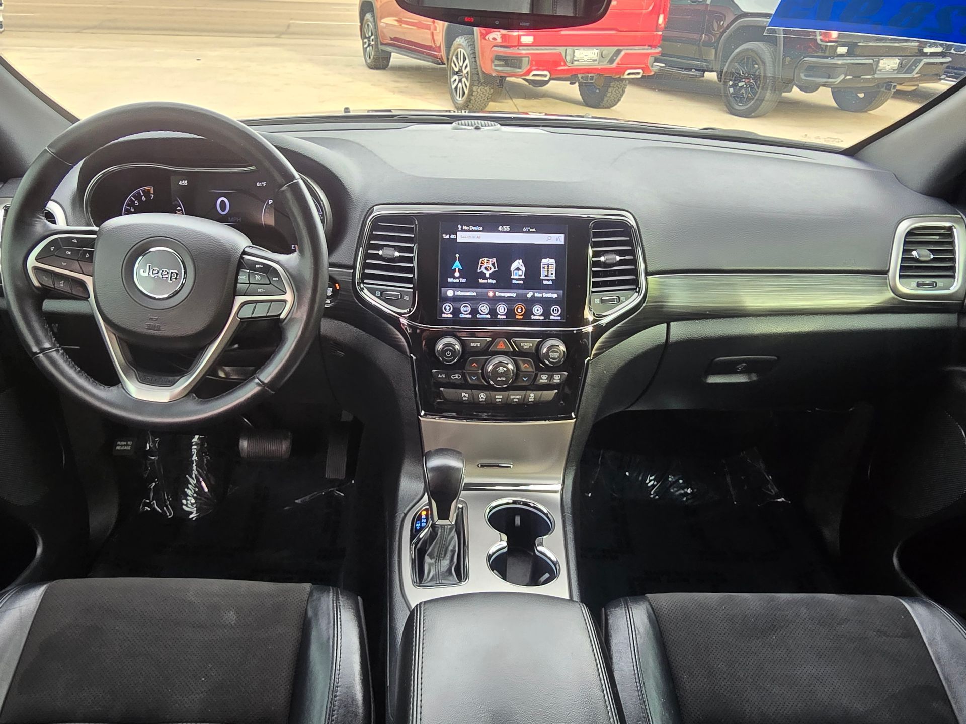 Interior view of a black Jeep Grand Cherokee dashboard, including steering wheel, infotainment screen, and center console.
