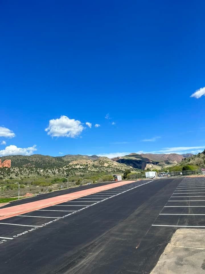 Empty asphalt parking lot with mountain backdrop under bright blue sky.