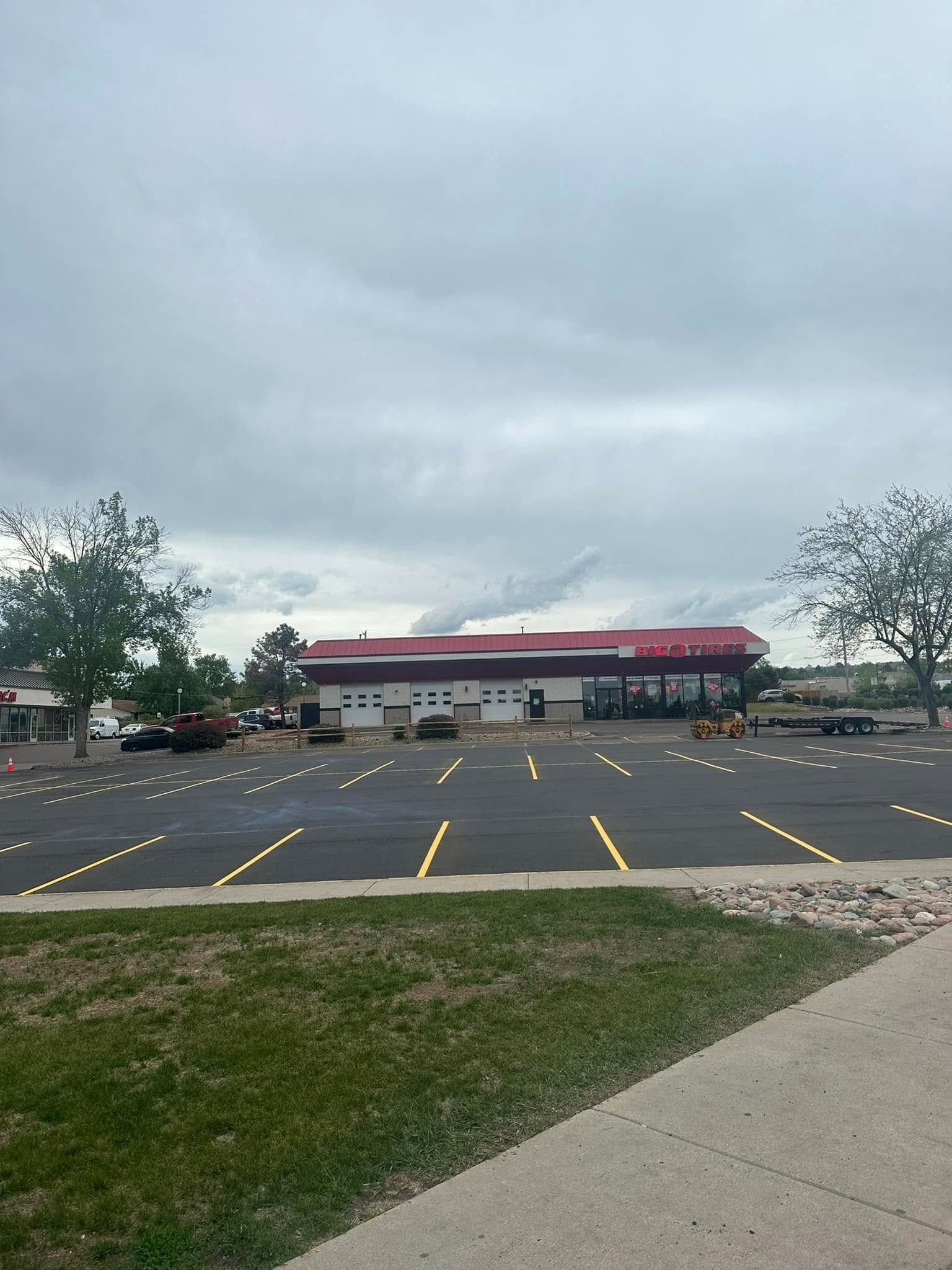 Large commercial building with a red and white facade, surrounded by an empty parking lot on a cloudy day.