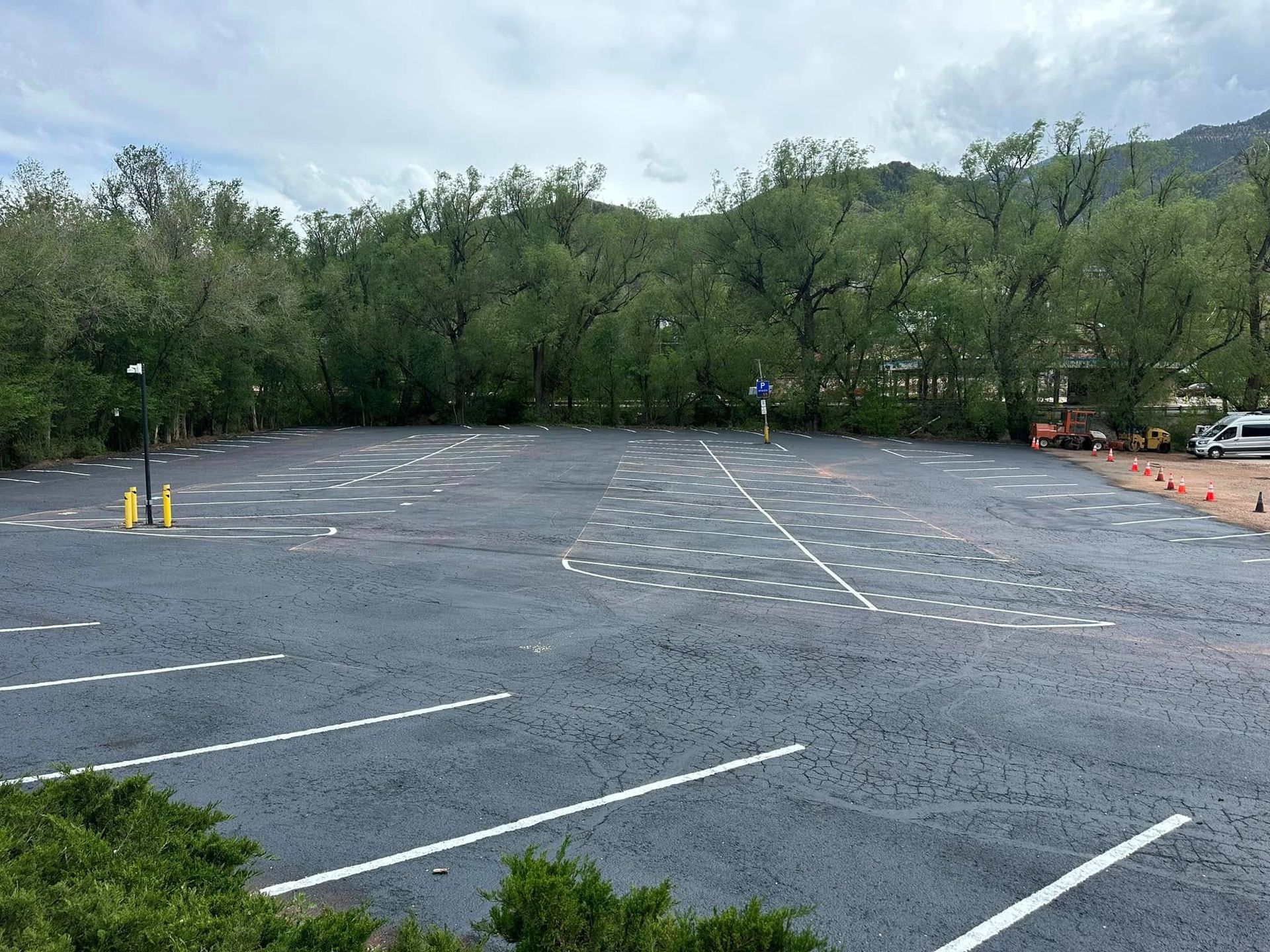 Empty parking lot with trees in background; person standing in center.
