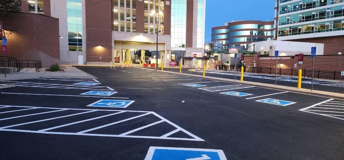 Parking lot with handicap spaces in front of a modern building with a clear glass facade.