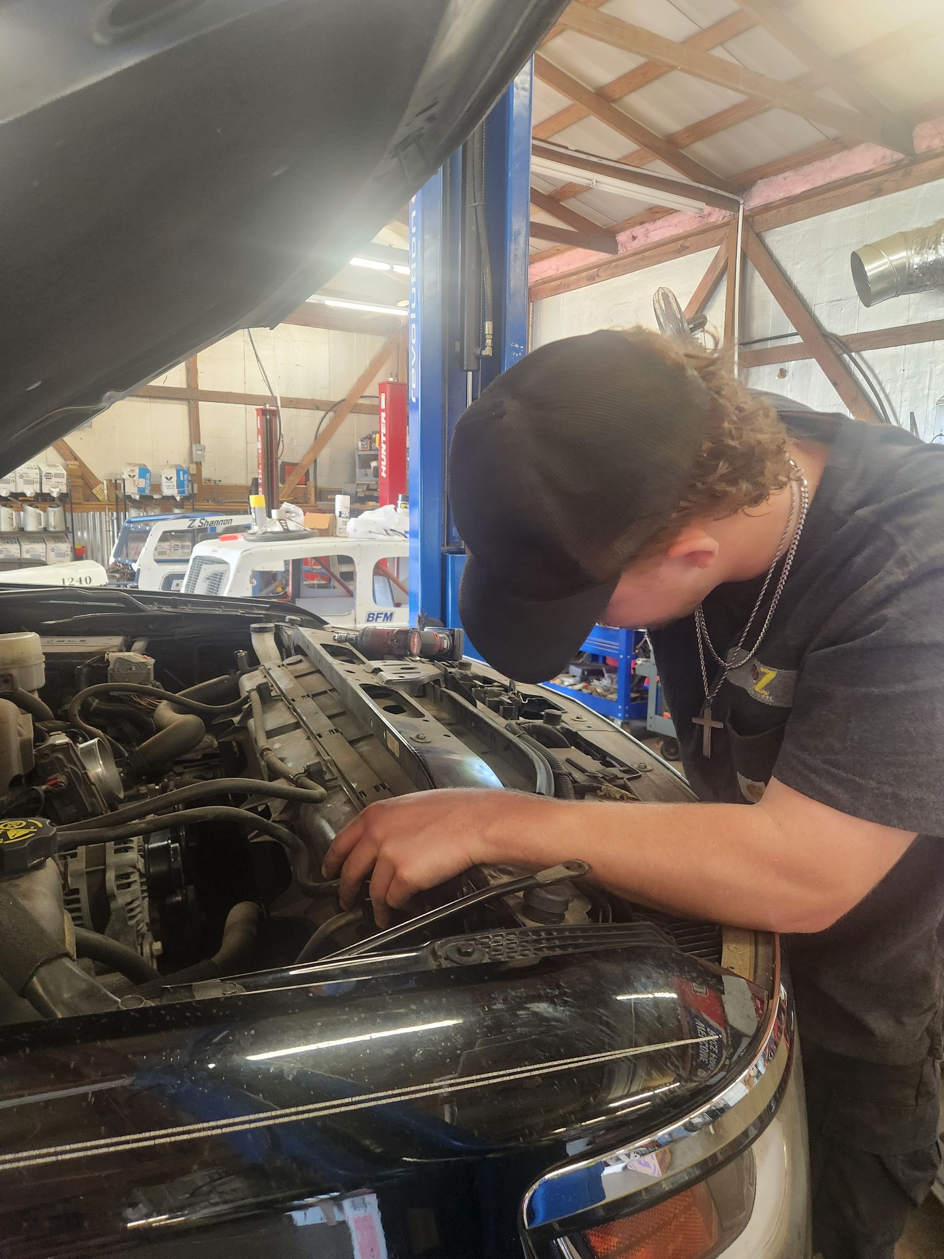Person working under the hood of a black car in a garage