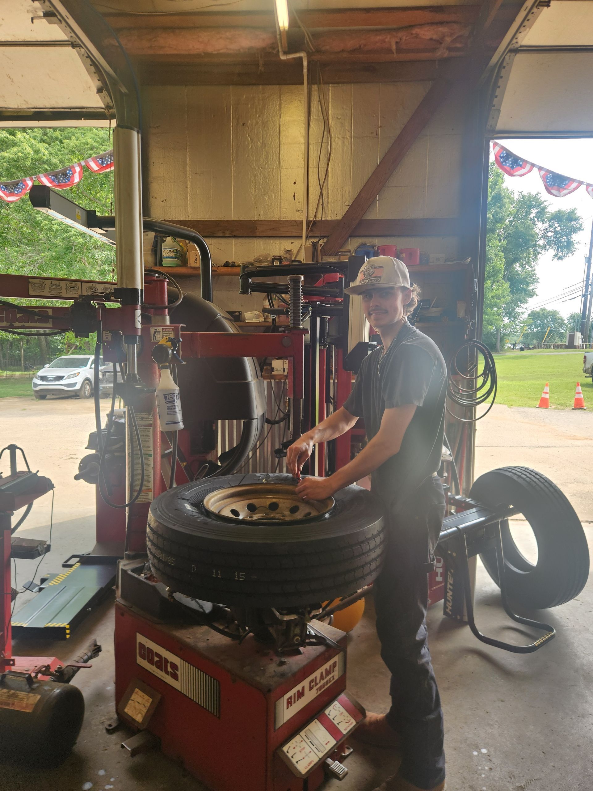 Mechanic adjusting a tire on a red tire-changing machine inside a garage
