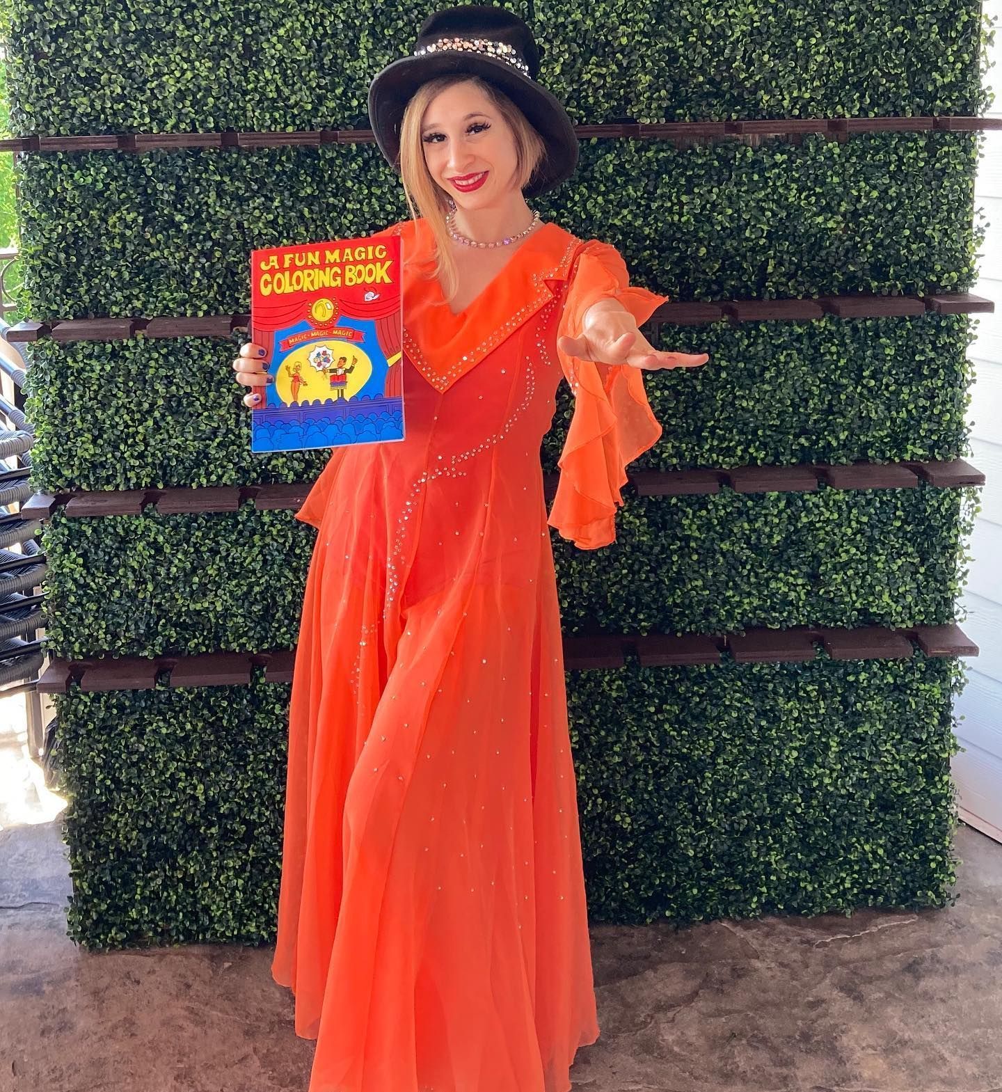 A woman in an orange dress is holding a book.