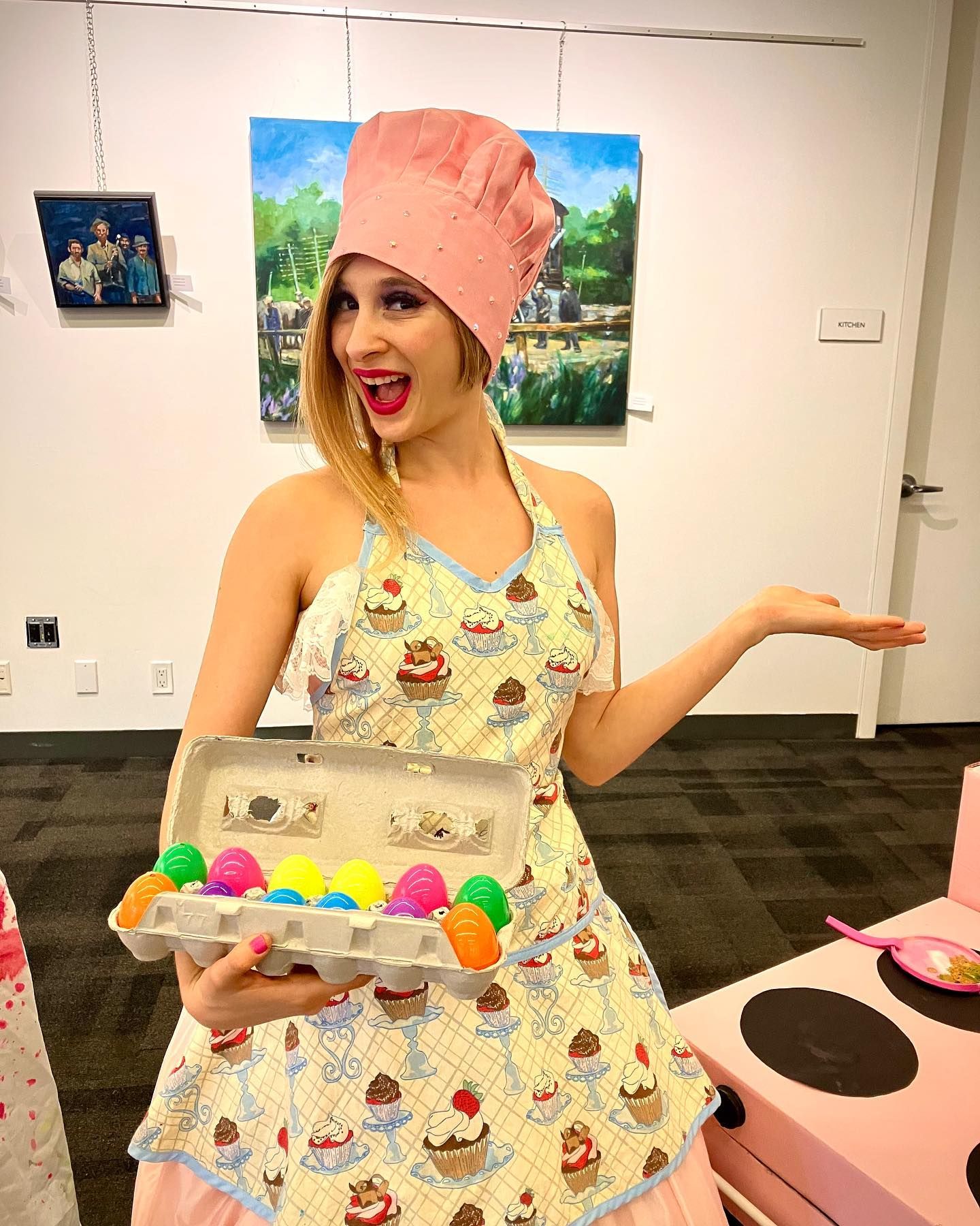A woman in an apron and chef 's hat is holding a box of eggs.