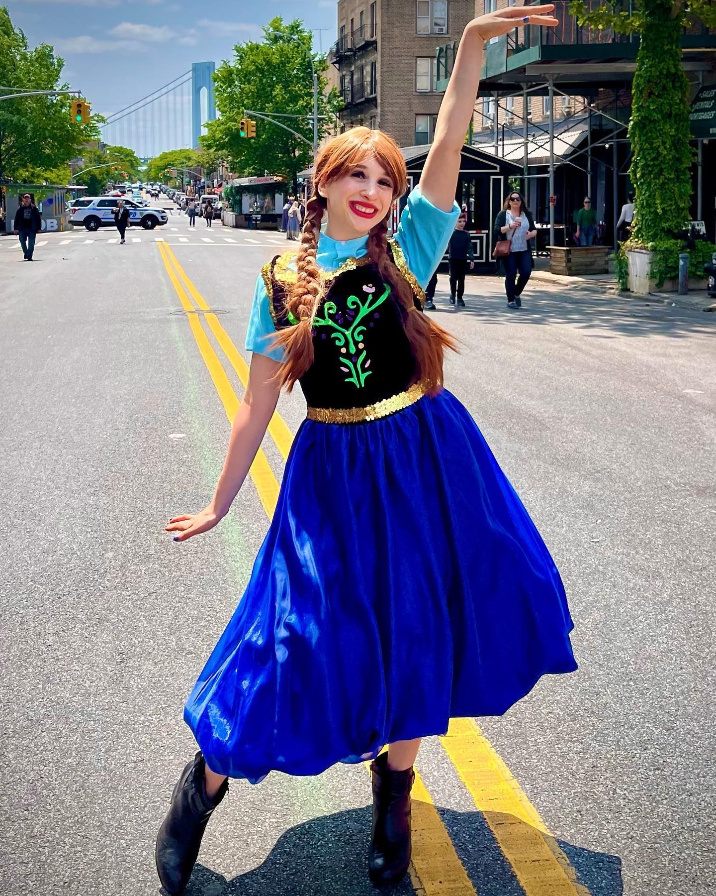 A woman dressed as anna from frozen is standing on a city street.