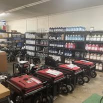 Generators displayed in a warehouse setting, many with red casings, on shelves with various supplies.