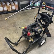 Black and yellow pressure washer on a cart.