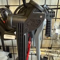 Black industrial spray guns hanging on a metal rack.