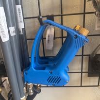 Blue pressure washer gun hanging on a metal grid, alongside plumbing pipes.