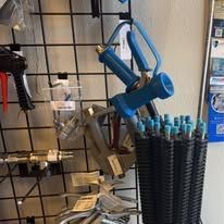 Blue spray gun and nozzles displayed on a wire rack.