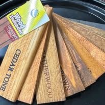 Wooden stain samples, fanned out, showcasing various wood tones with product branding visible.