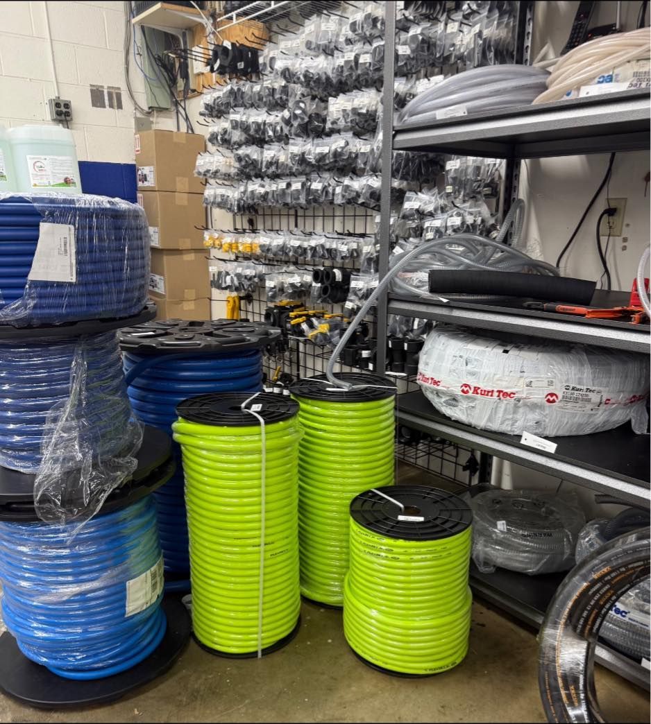 Spools of blue and neon green cable in a warehouse, with shelving in the background.