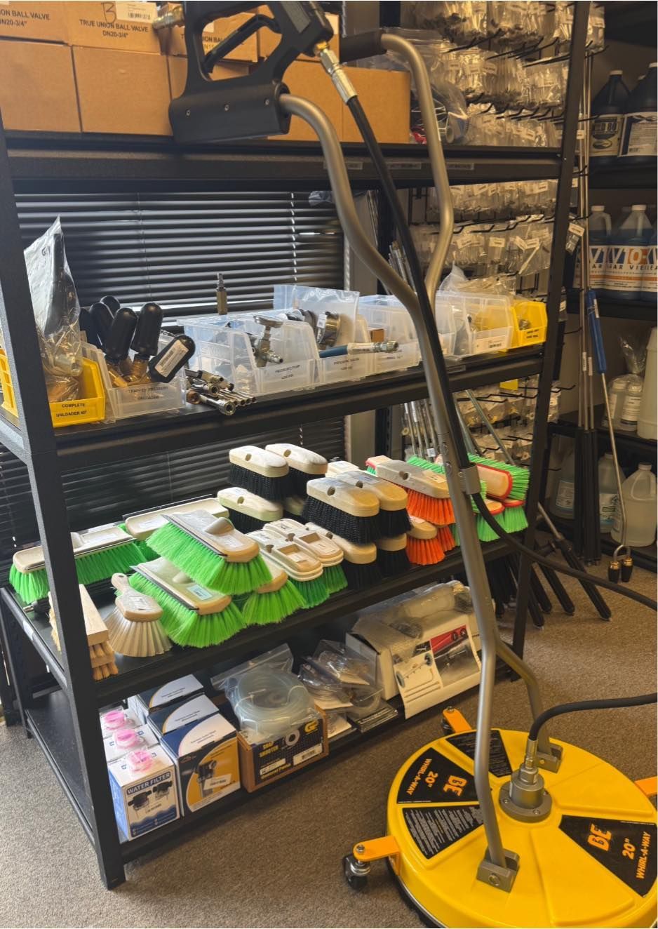 A yellow surface cleaner with accessories and cleaning supplies on shelves in a store.