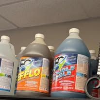 Cleaning product bottles on a shelf. One orange label reads 