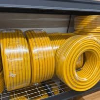 Yellow electrical wire spools neatly stacked on a metal shelf.