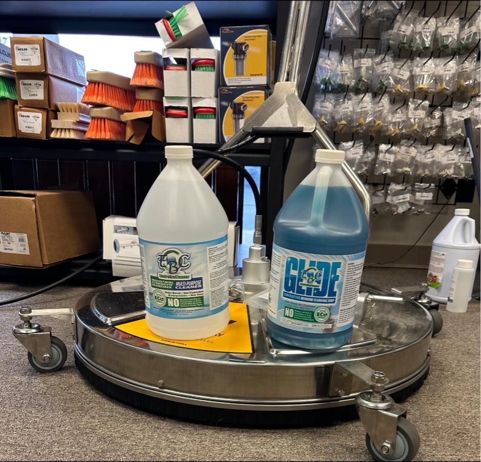Two large detergent bottles on a pressure washer with brushes and store shelves in the background.