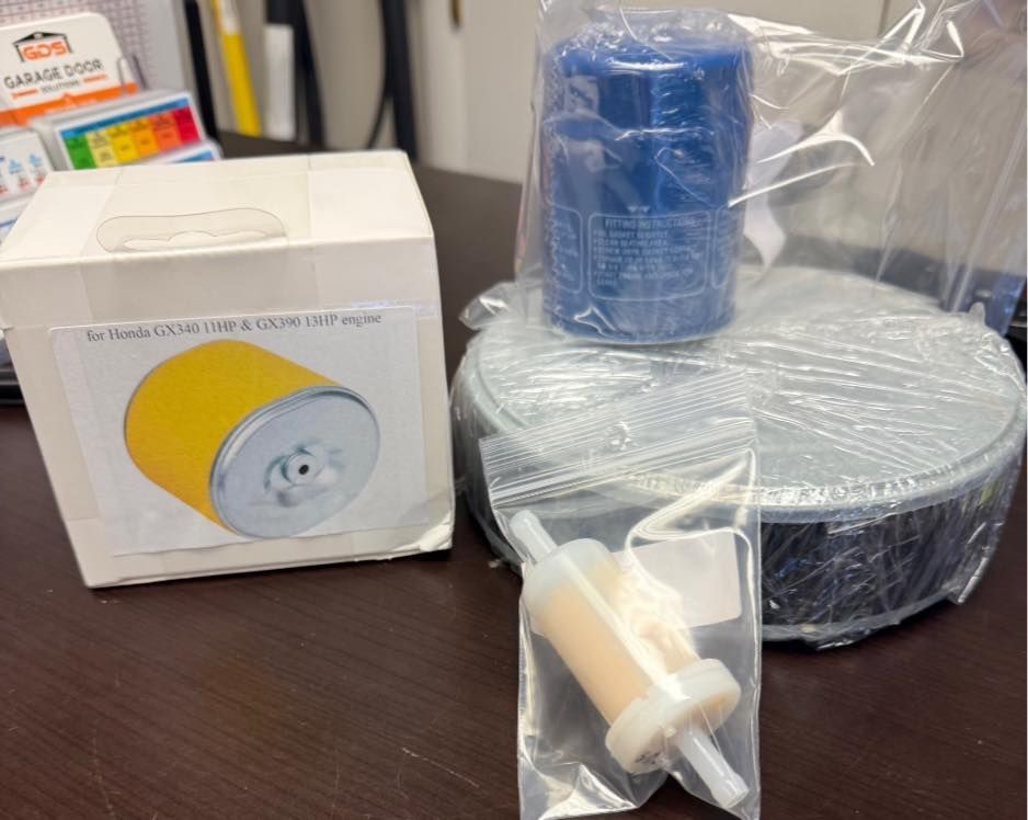 Various automotive parts: air filter, oil filter, fuel filter, and an unidentified part, on a table.