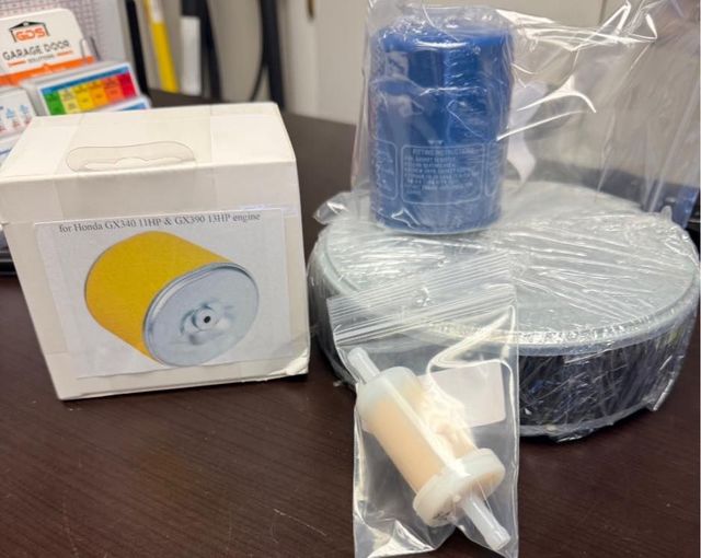 Various automotive parts: air filter, oil filter, fuel filter, and an unidentified part, on a table.