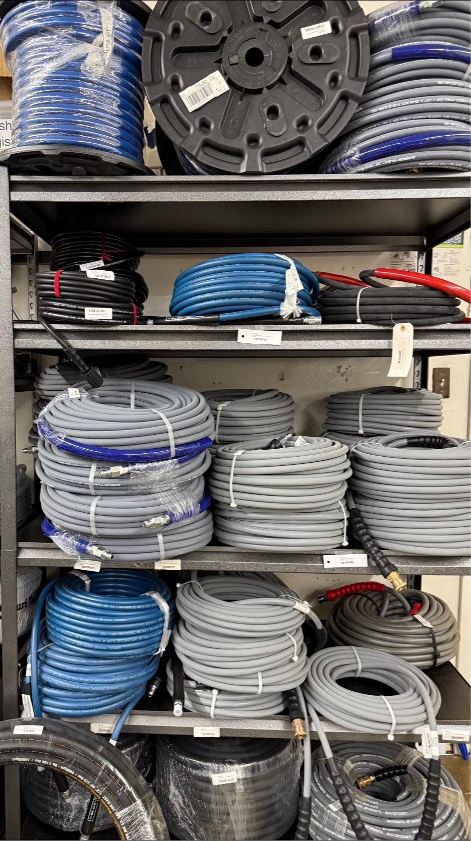 Shelves stocked with various coiled electrical cables in blue, gray, and black.