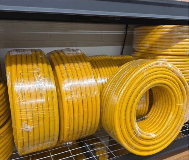 Yellow electrical cable rolls, neatly stacked on a metal shelf.