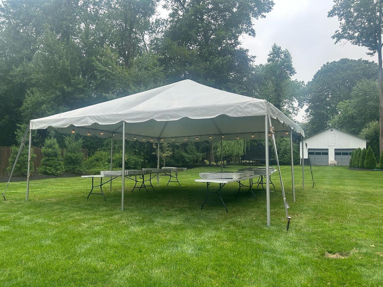 a white tent with tables and chairs in a grassy area