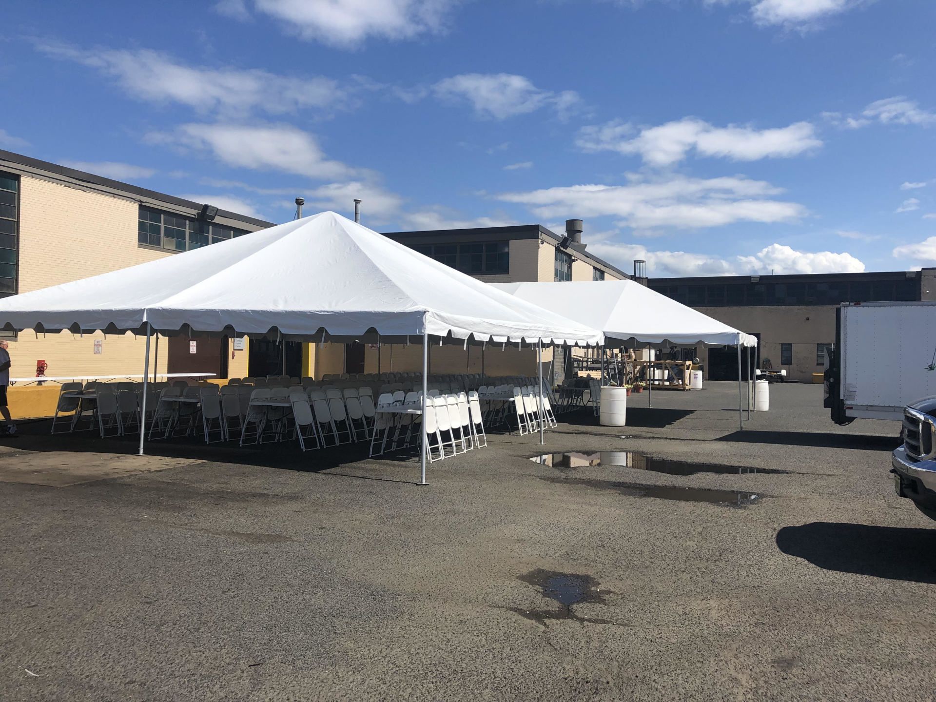 a white tent with chairs and tables in front of a building