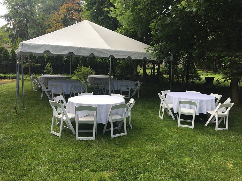 a white tent with tables and chairs in a grassy area