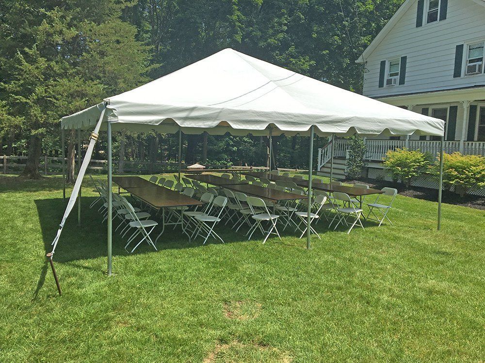 a tent with tables and chairs in a yard