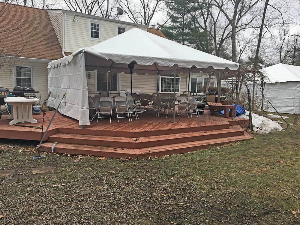 a white tent on a deck with a house in the background