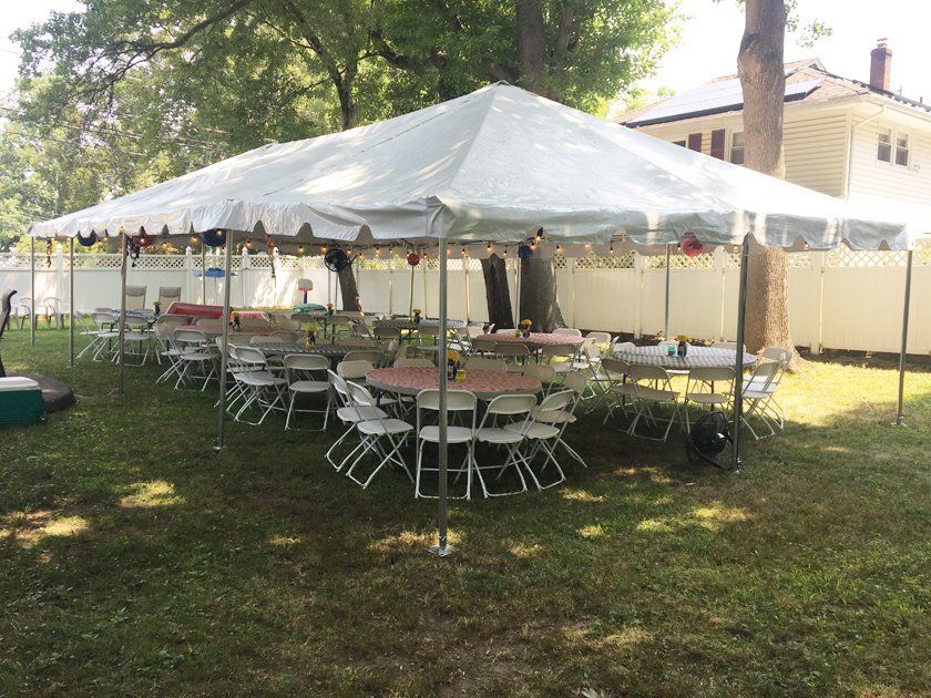 a white tent with tables and chairs in a yard