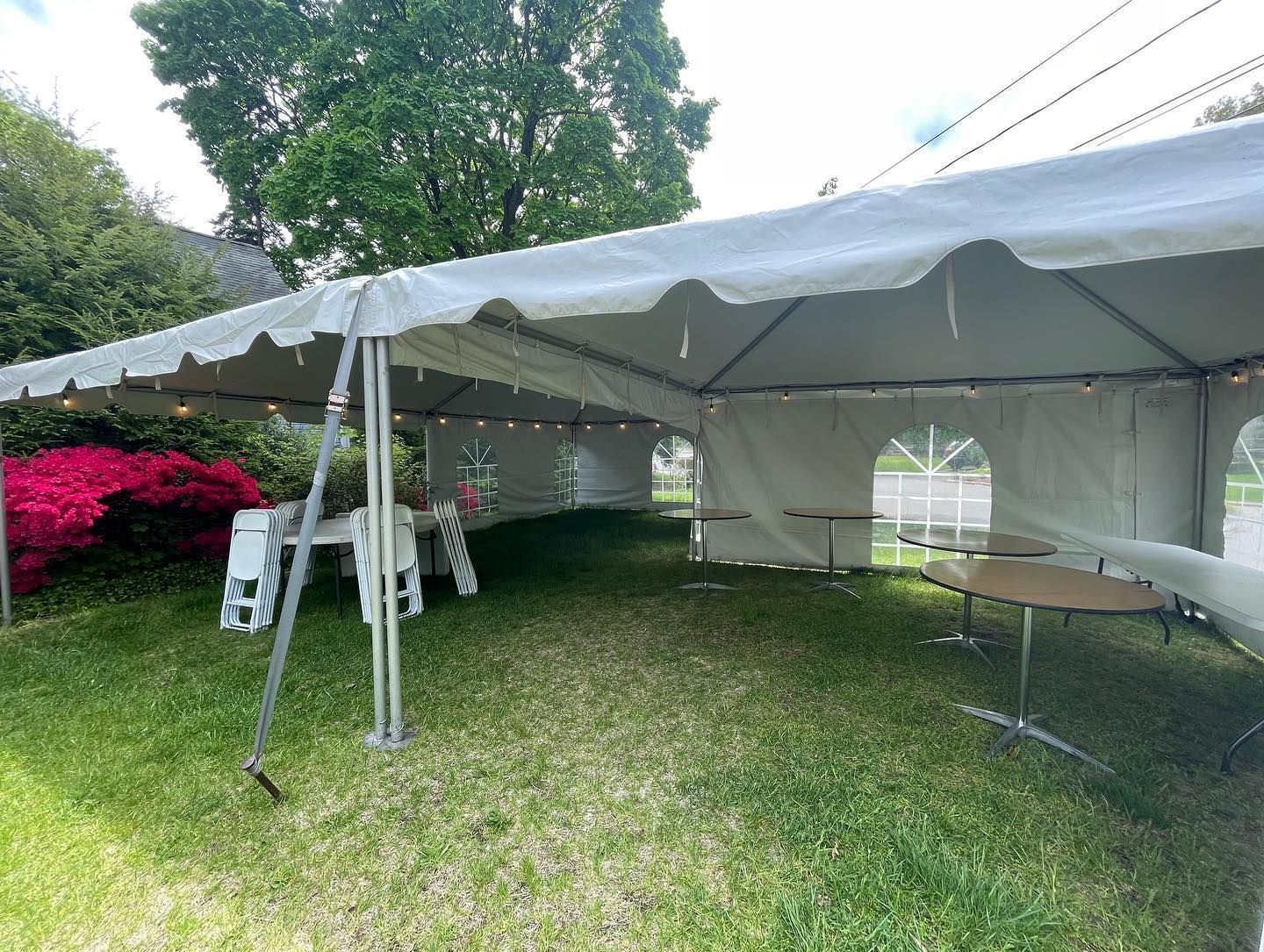 a white tent with lights and tables in a yard
