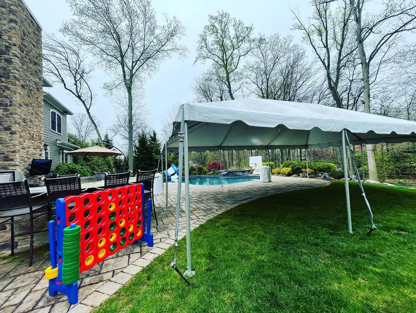 a lawn with a white tent and a pool in the background