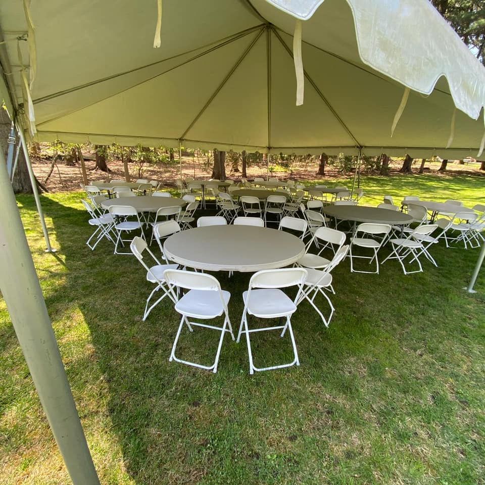 a white tent with chairs and tables on grass
