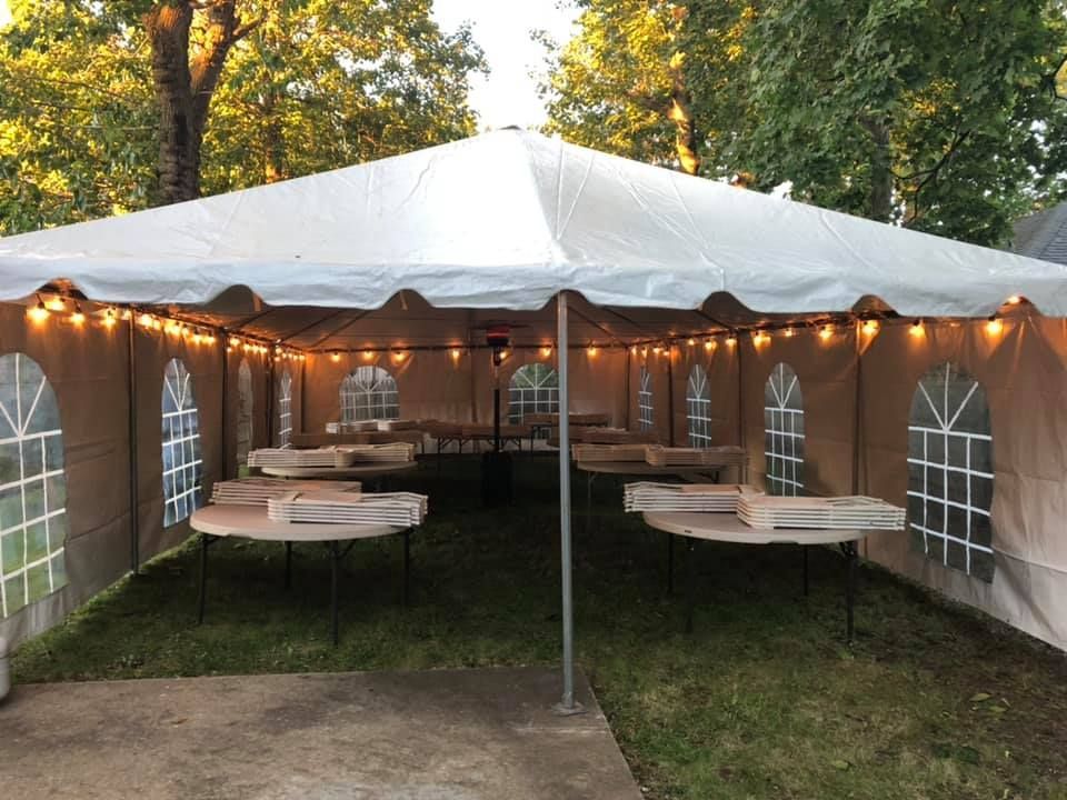 a white tent with lights and tables in the middle